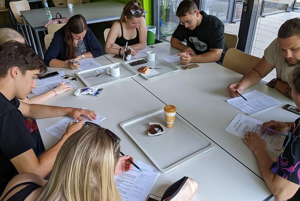 Studierende sitzen um einen Tisch und arbeiten