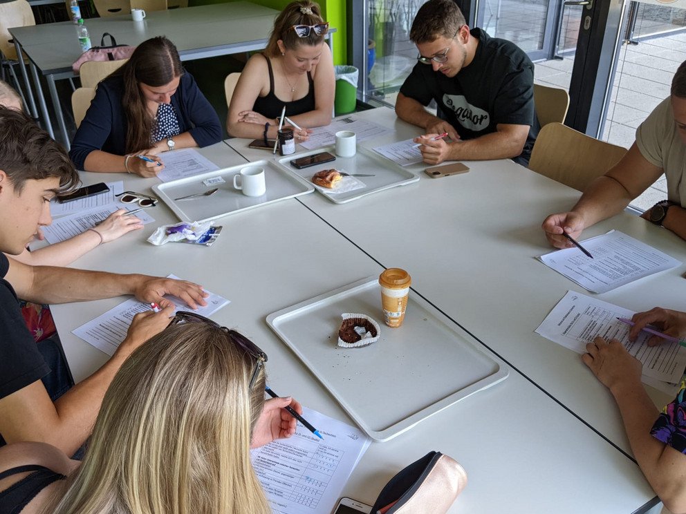 Studierende sitzen um einen Tisch und arbeiten