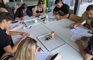 Studierende sitzen um einen Tisch und arbeiten