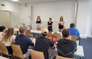 Vortrag drei Studierender vor Gruppe
