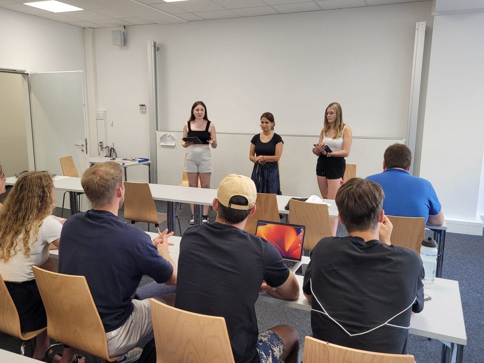 Vortrag drei Studierender vor Gruppe