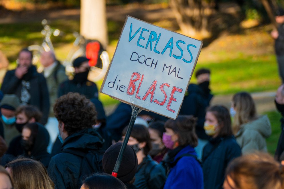 Demonstrant hält Schild mit der Aufschrift: "Verlass doch mal die Blase" hoch.