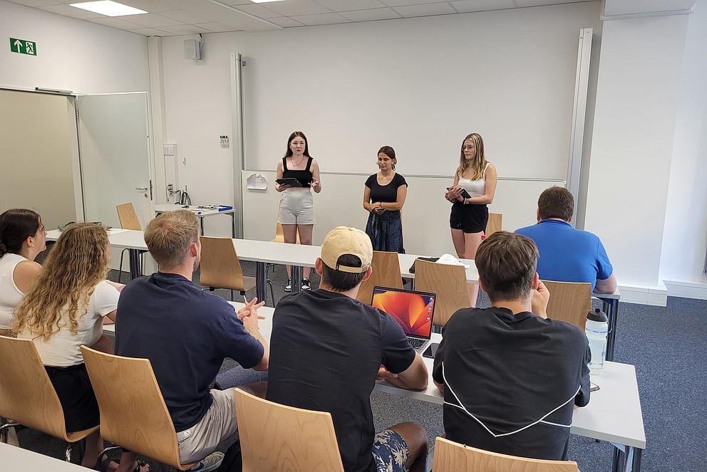 Vortrag drei Studierender vor Gruppe